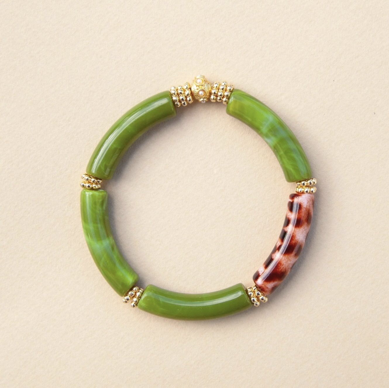Green bracelet with tortoiseshell accents on a beige background